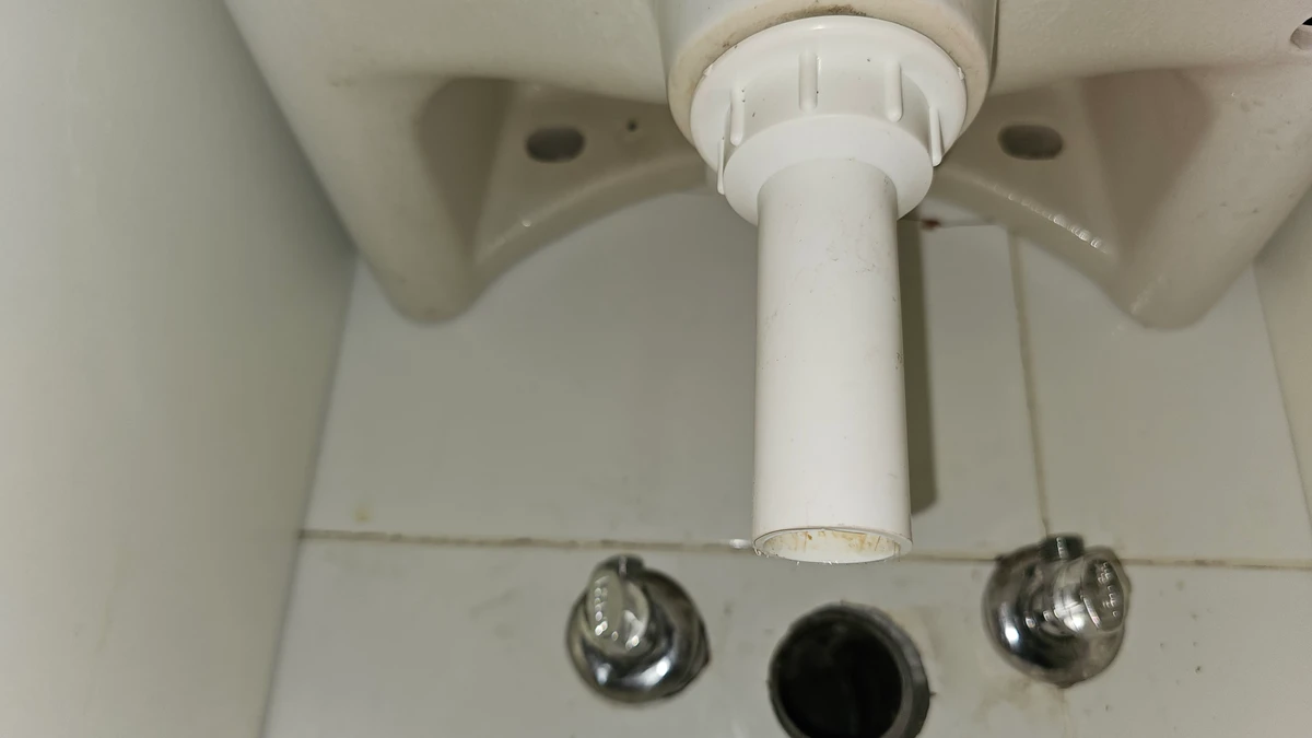 Rurka spustowa w gnieździe syfonu pod umywalką podczas wymiany