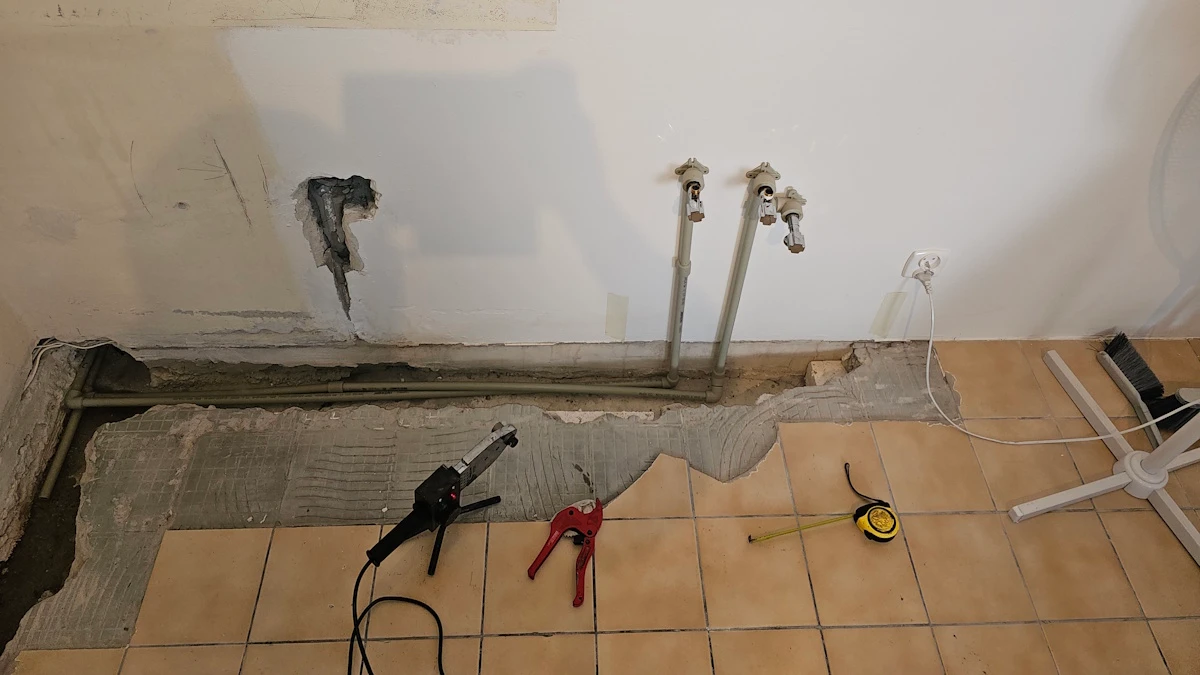 Bruzdy w ścianie i podłodze kuchni z nowymi rurami wody, obok zgrzewarka i obcinak do rur
